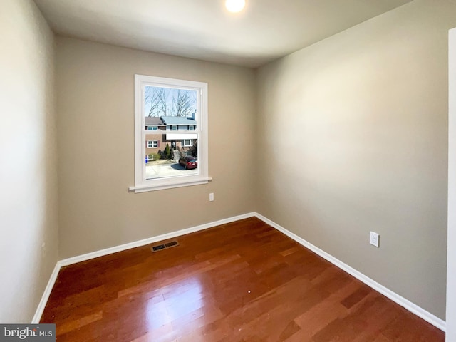 empty room with visible vents, baseboards, and dark wood finished floors