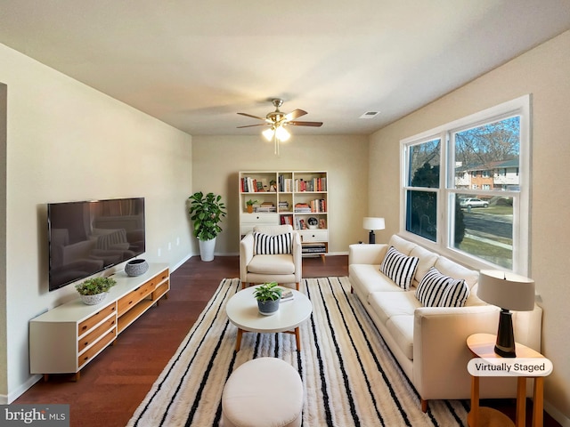 living area with visible vents, baseboards, wood finished floors, and a ceiling fan