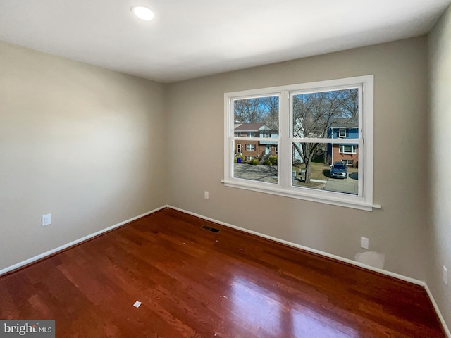 unfurnished room featuring wood finished floors, visible vents, and baseboards