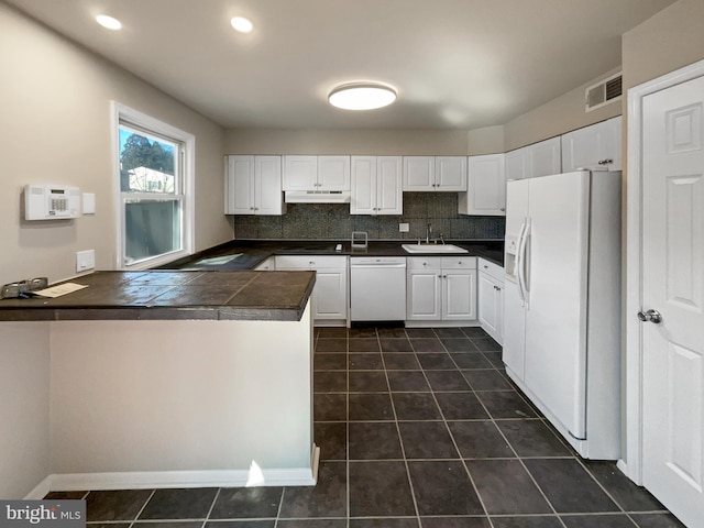 kitchen featuring white appliances, visible vents, a peninsula, a sink, and white cabinets