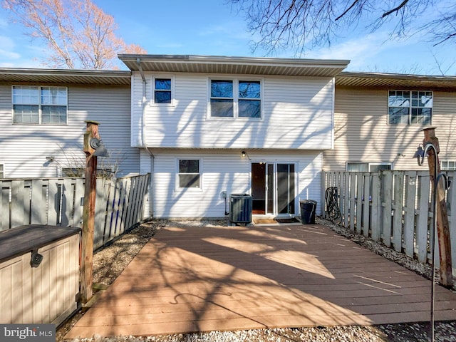 rear view of property with a fenced backyard, central AC, and a wooden deck