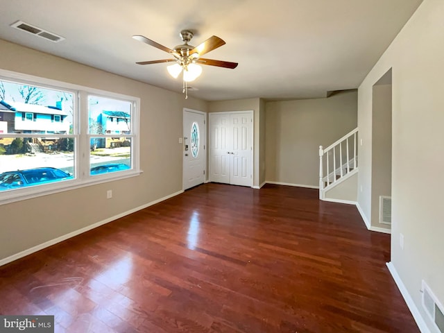 foyer featuring visible vents, baseboards, wood finished floors, and stairs