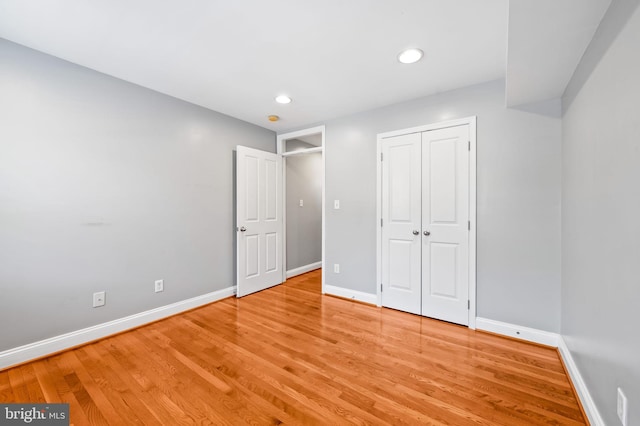 unfurnished bedroom featuring recessed lighting, a closet, baseboards, and light wood-style flooring