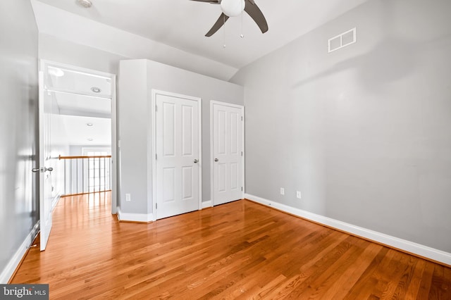 unfurnished bedroom featuring visible vents, two closets, baseboards, and light wood-style floors