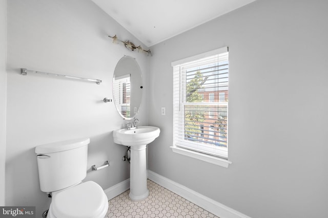 half bathroom featuring toilet, lofted ceiling, and baseboards