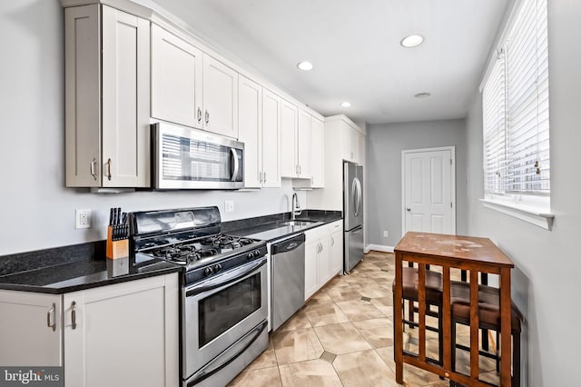 kitchen with a sink, stainless steel appliances, white cabinets, and light tile patterned floors