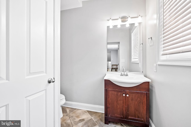 half bath featuring vanity, toilet, and baseboards