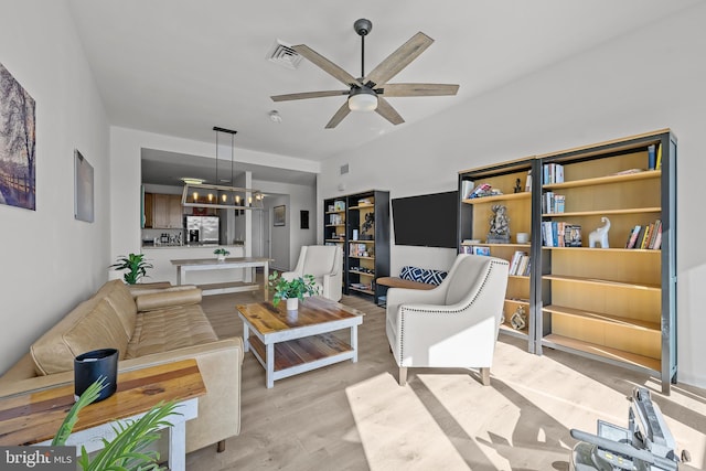 living room with visible vents, ceiling fan, and light wood-style flooring