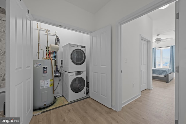 laundry room with a ceiling fan, stacked washing maching and dryer, laundry area, electric water heater, and light wood-type flooring