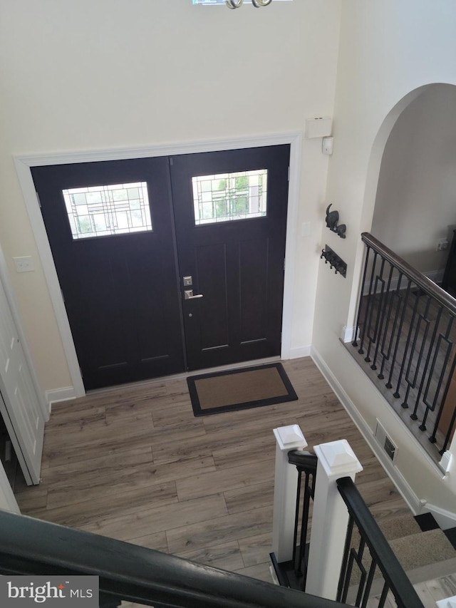 entryway featuring stairway, wood finished floors, visible vents, baseboards, and arched walkways