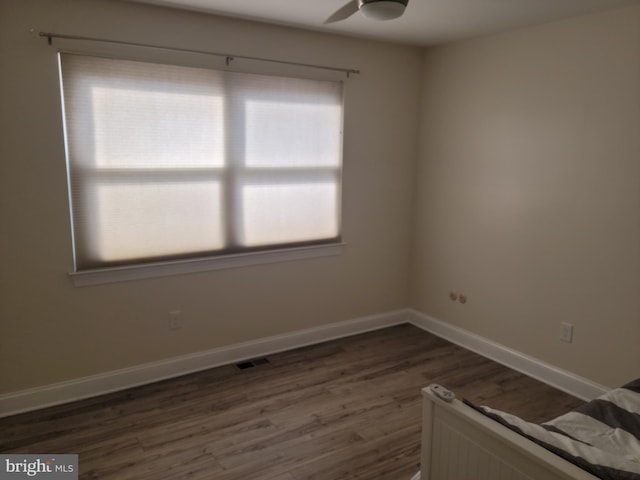 spare room with dark wood-type flooring, visible vents, baseboards, and ceiling fan