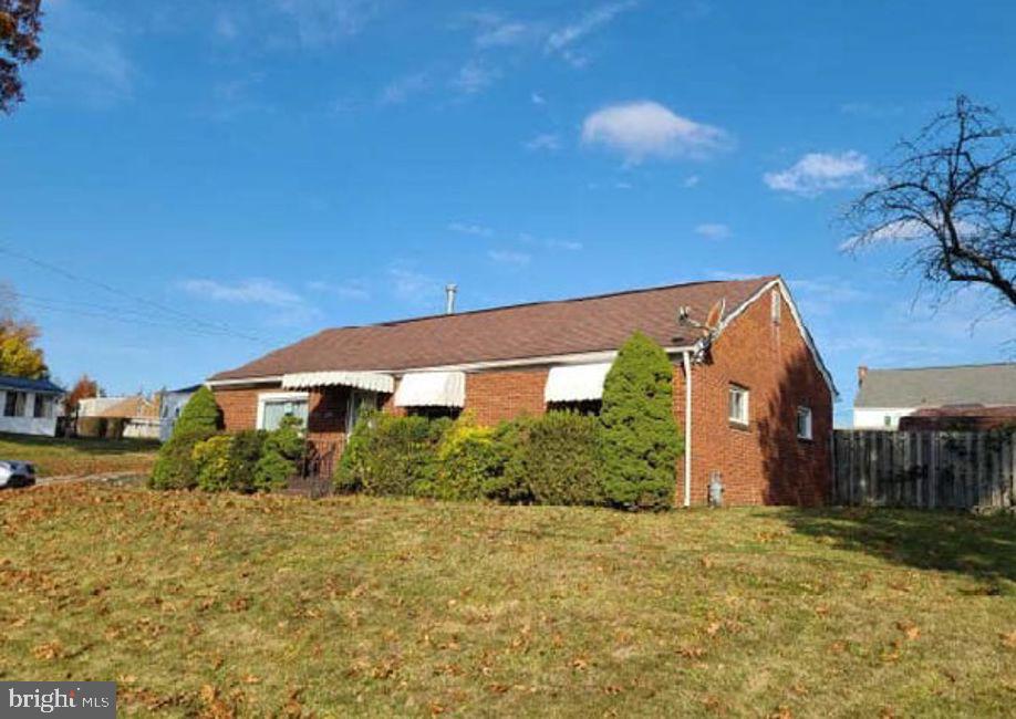 view of front of home featuring brick siding, a front lawn, and fence