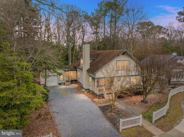 view of front of house featuring driveway, fence, a shingled roof, a garage, and a chimney