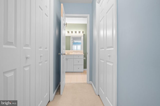 hall with light colored carpet and baseboards