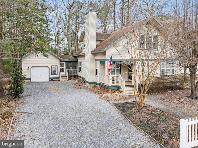 view of front of property with roof with shingles, driveway, a porch, an attached garage, and a chimney