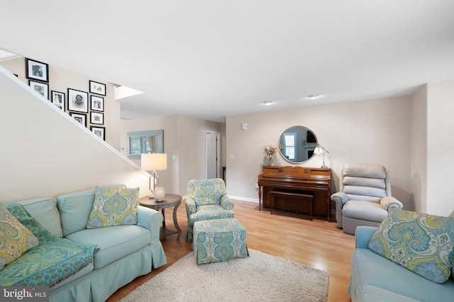 living room with stairway, baseboards, and light wood finished floors