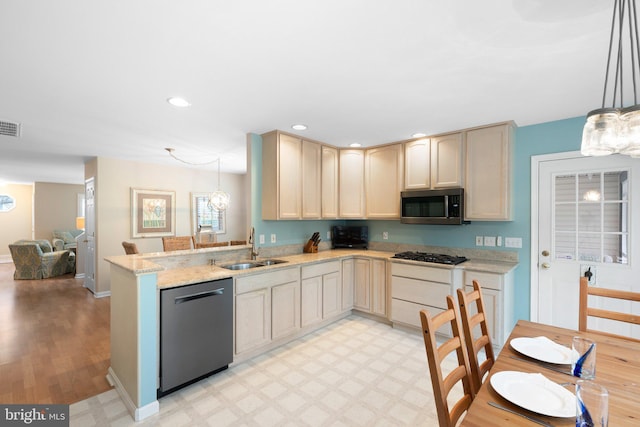 kitchen with light floors, recessed lighting, appliances with stainless steel finishes, a peninsula, and a sink