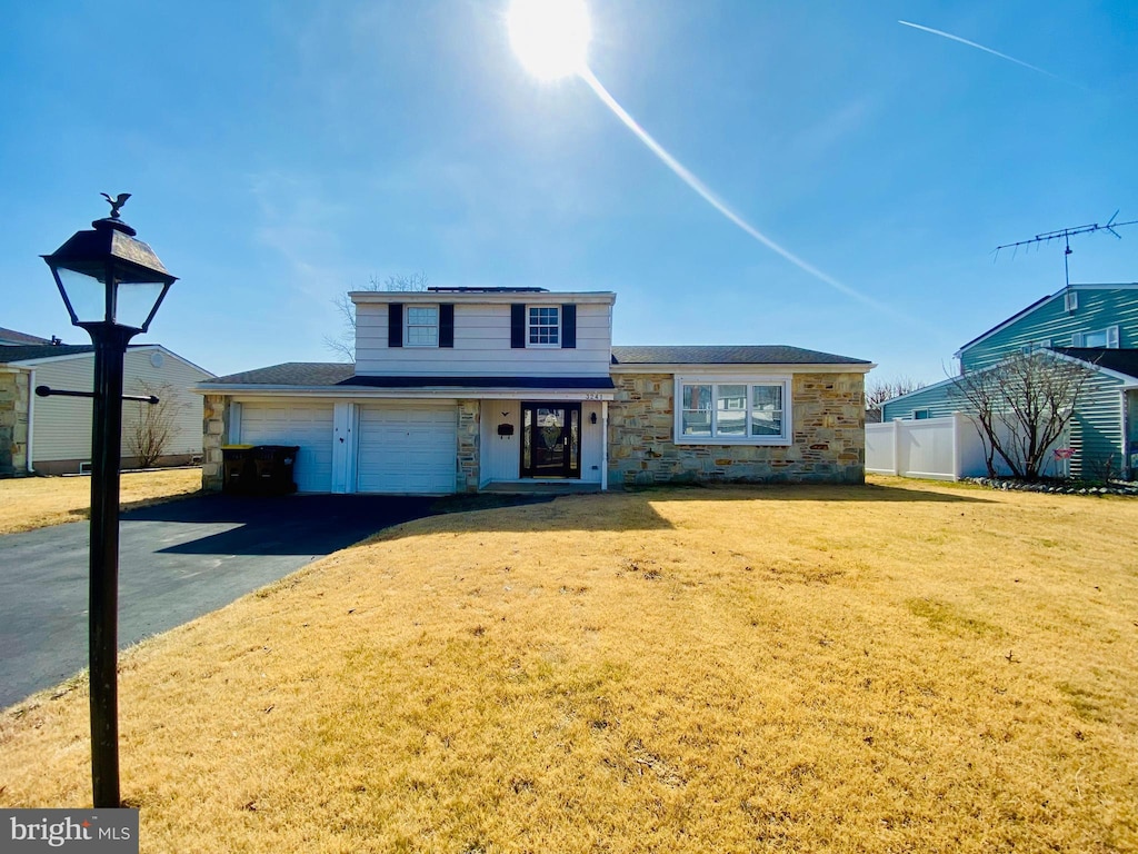 view of front of property with fence, a front lawn, a garage, stone siding, and aphalt driveway