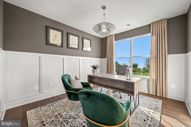 home office with visible vents, wainscoting, a decorative wall, and wood finished floors