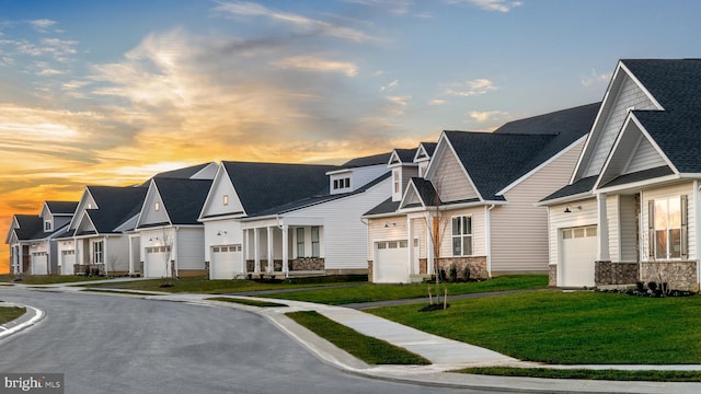 view of property featuring a garage, a lawn, a residential view, and stone siding