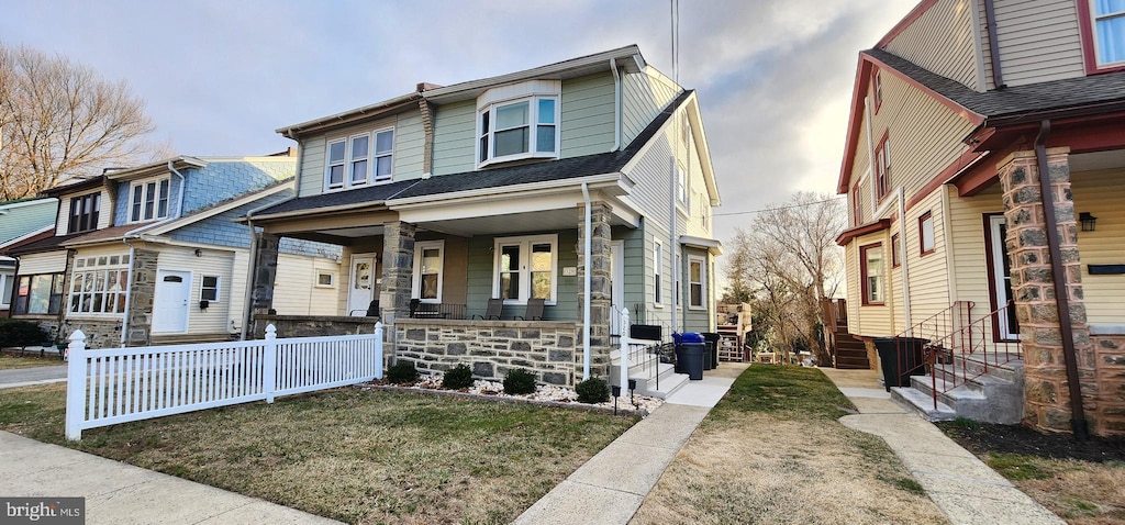 view of front of home featuring a porch, entry steps, and a front lawn