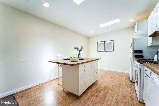 kitchen with white appliances, light wood-style floors, white cabinets, and butcher block counters