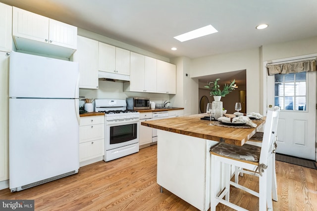 kitchen with under cabinet range hood, white appliances, butcher block countertops, and light wood-style flooring