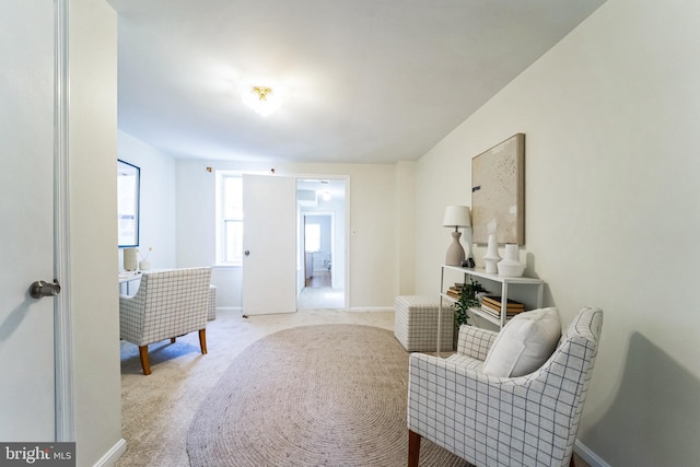 living area featuring baseboards and light carpet