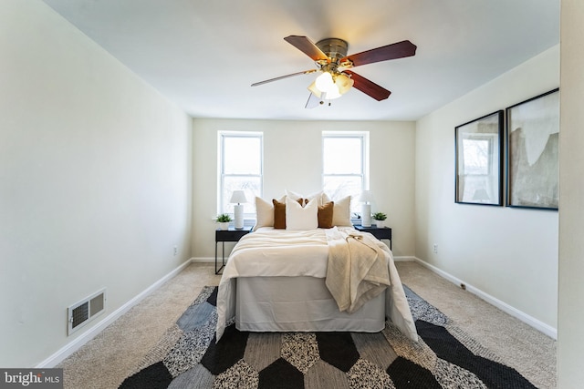 carpeted bedroom with visible vents, baseboards, and a ceiling fan