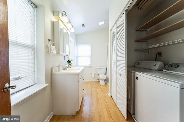 laundry room featuring visible vents, light wood-type flooring, laundry area, washer and dryer, and a sink