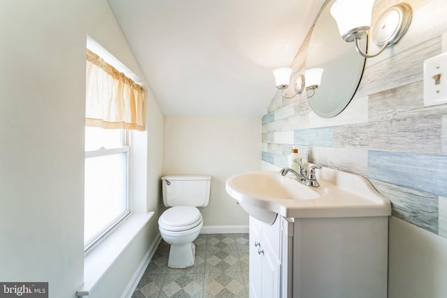 half bath with baseboards, toilet, lofted ceiling, and vanity