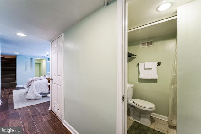 ensuite bathroom featuring toilet, baseboards, visible vents, and wood finish floors