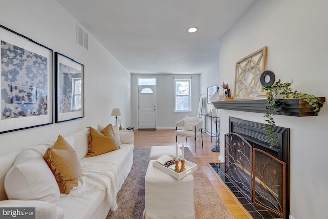 living room with visible vents, baseboards, a fireplace with flush hearth, recessed lighting, and wood finished floors