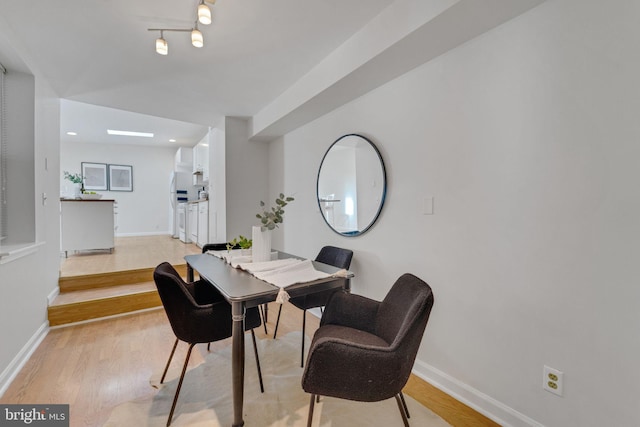 dining space with baseboards and light wood finished floors