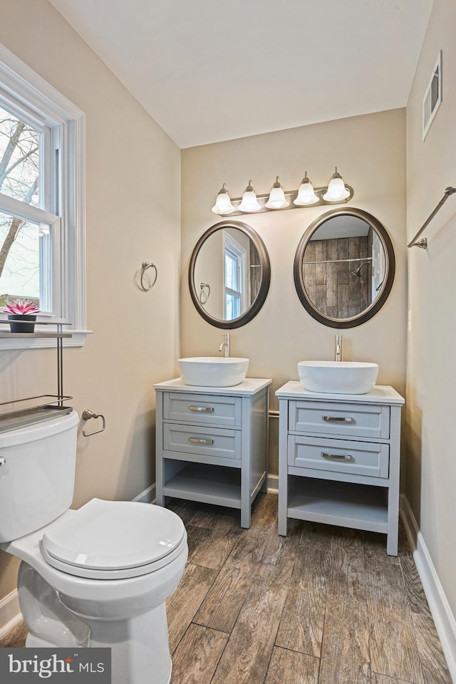 full bath with baseboards, toilet, wood finished floors, and vanity