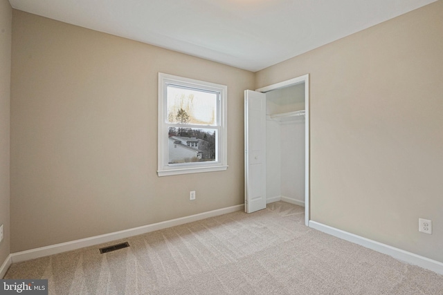 unfurnished bedroom with visible vents, baseboards, carpet, and a closet