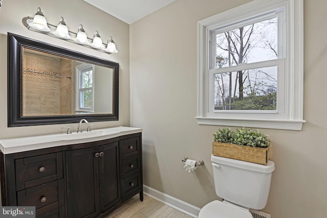 bathroom with vanity, toilet, wood finished floors, and baseboards