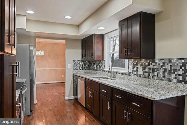 kitchen with dark wood-type flooring, dark brown cabinetry, dishwasher, decorative backsplash, and a sink