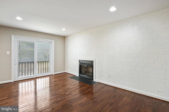 unfurnished living room featuring dark wood-type flooring, a fireplace with flush hearth, recessed lighting, and baseboards