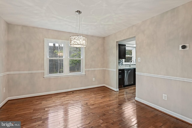 unfurnished dining area with an inviting chandelier, dark wood-type flooring, visible vents, and baseboards