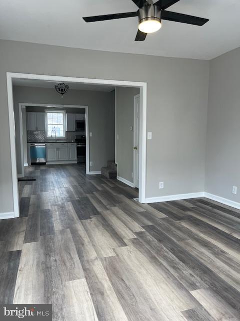 unfurnished living room with baseboards, ceiling fan, and dark wood-style flooring