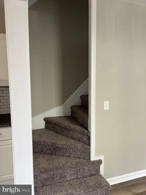 stairs with wood finished floors and baseboards