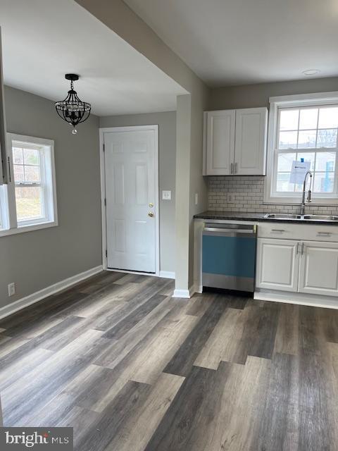 kitchen with dishwashing machine, backsplash, white cabinets, and a sink