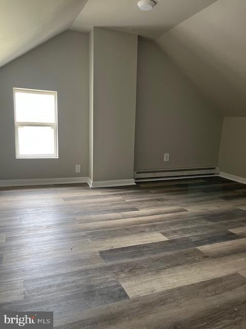 additional living space with baseboards, a baseboard heating unit, lofted ceiling, and wood finished floors