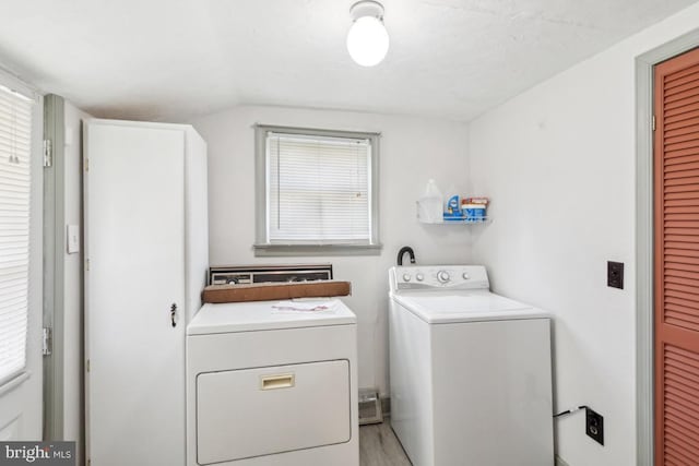 laundry room with wood finished floors, washer and dryer, laundry area, and a healthy amount of sunlight