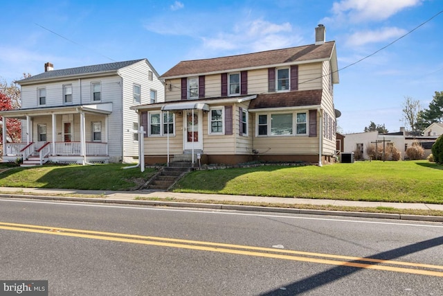 view of front of house with central AC unit, a chimney, and a front lawn