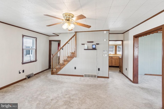 unfurnished living room featuring crown molding, a ceiling fan, visible vents, and carpet floors
