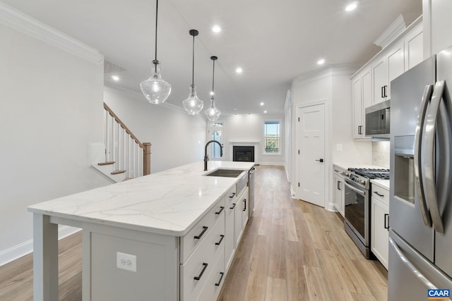 kitchen featuring a sink, crown molding, a center island with sink, and stainless steel appliances