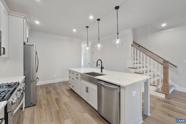 kitchen with crown molding, a center island with sink, white cabinets, stainless steel appliances, and a sink