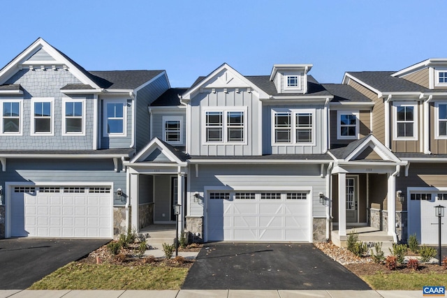 multi unit property with aphalt driveway, a garage, and stone siding